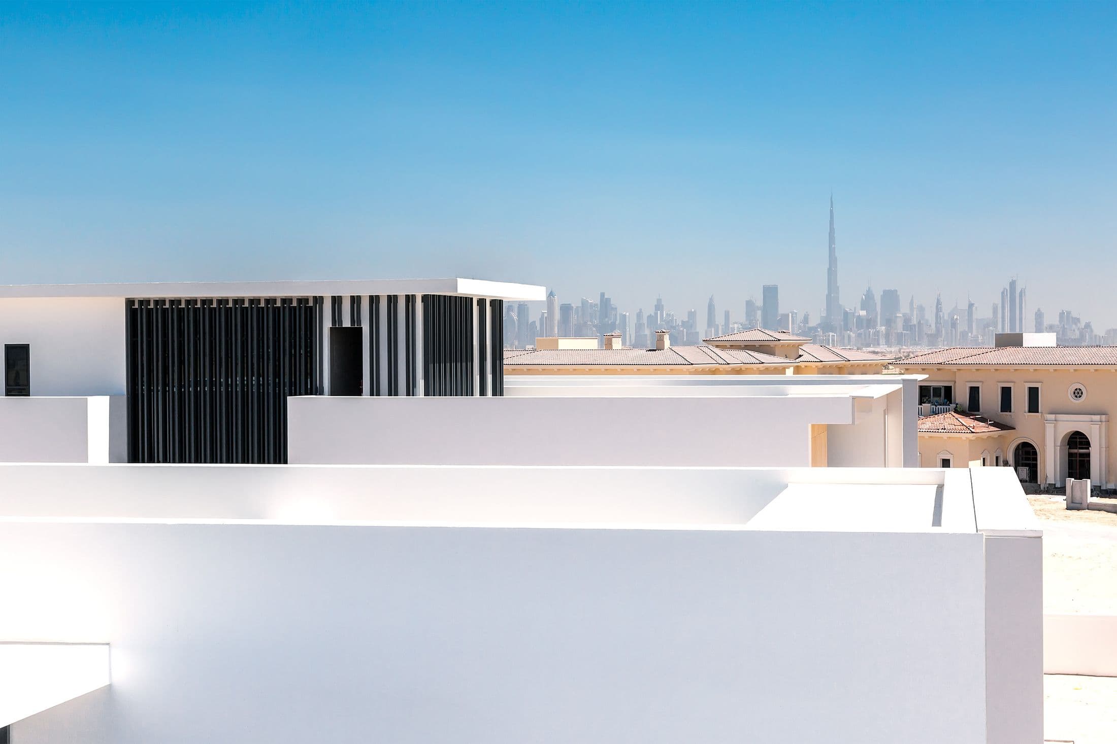 Minimal white residential architecture with the Dubai skyline in the distance